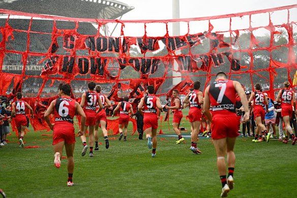 Zach Merret (No.7) is the last player heading through Essendon’s ripped banner.
