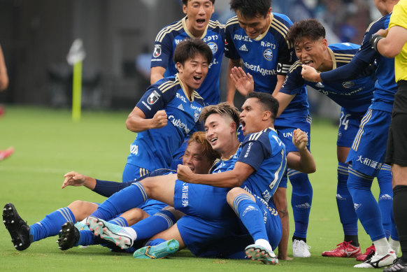 Machida Zelvia players celebrate after scoring a goal.