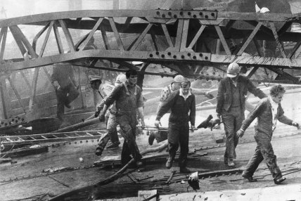 Westgate Bridge collapse, 1970: A victim is carried from a massive pile of twisted girders by civil defence men and workmates. 