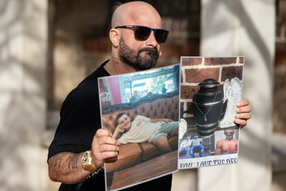 Exaven Desisto holds up a photo of his son, and his son’s urn, as he leaves court.
