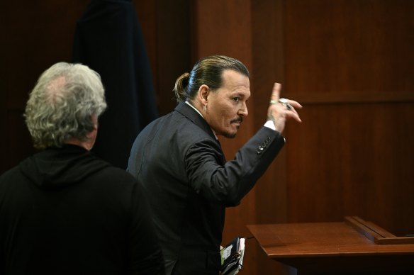Actor Johnny Depp gestures as he walks out of the courtroom.