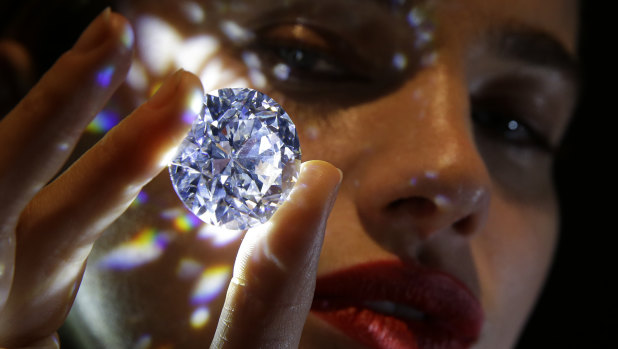 A 102.34, carat, D colour and flawless white diamond held by a model is displayed at Sotheby's auction house in London.