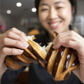 Fraances Song breaks open a chocolate croissant at Layers Sydney in St Leonards.