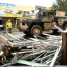 An army vehicle drives past debris in the flood-affected city centre of Lismore, NSW, in March.