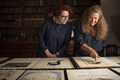 Margot Riley (left), curator at the State Library of NSW, inspects the sailing log belonging to Jack Earl, the grandfather of Tiare Tomaszewski (right). 