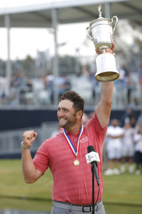 Jon Rahm celebrates with the US Open trophy.