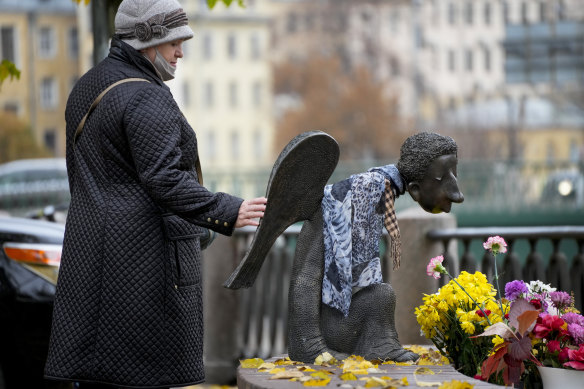 A woman touches the sculpture “Sad Angel”, a memorial for St Petersburg’s medical workers who died from coronavirus during their work.