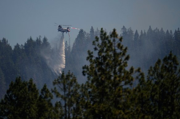 A firefighting aircraft drops water on a wildfire the day after a shooter ambushed and killed multiple firefighters.