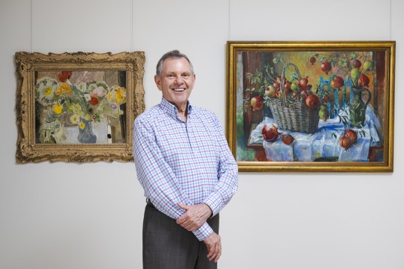 Philip Bacon with two artworks from his private collection: Still life, poppies, C. 1932, by Ivon Hitchens; and Pomegranates in a Basket, 1967, by Margaret Olley.
