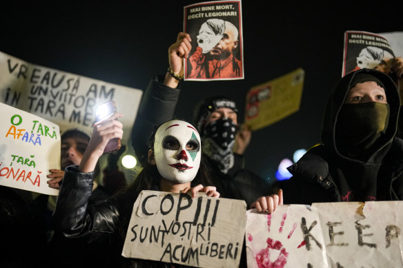 A woman wearing a mask holds a banner – “Your children are now free” – during a protest against Calin Georgescu.