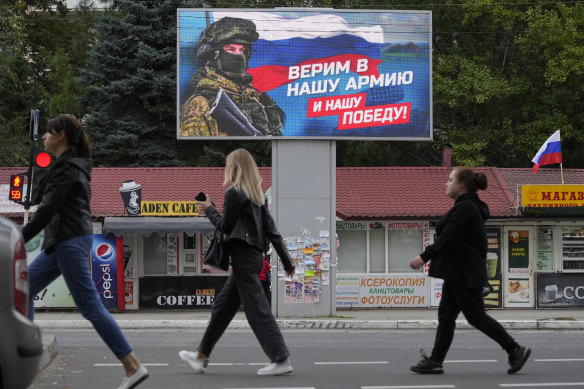 People walk past a billboard displaying a soldier and a Russian flag and reading ‘We believe in our army and our victory’ in Luhansk, Luhansk People’s Republic controlled by Russia-backed separatists, eastern Ukraine.