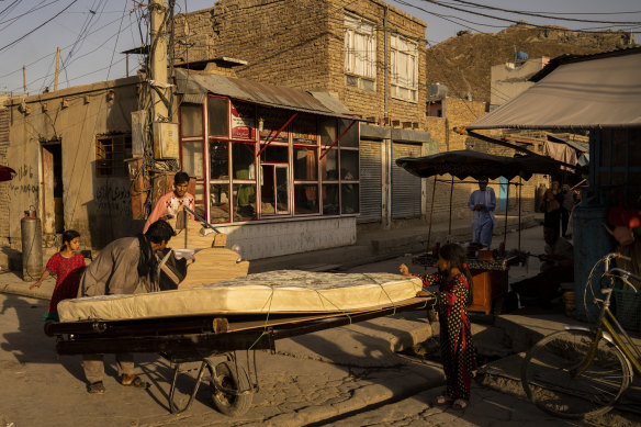 Two Afghan men push wheelbarrows loaded with furniture in Kharabat neighbourhood in Kabul, Afghanistan. A foundering economy, along with the coronavirus pandemic, has some families selling off furniture to get by. 