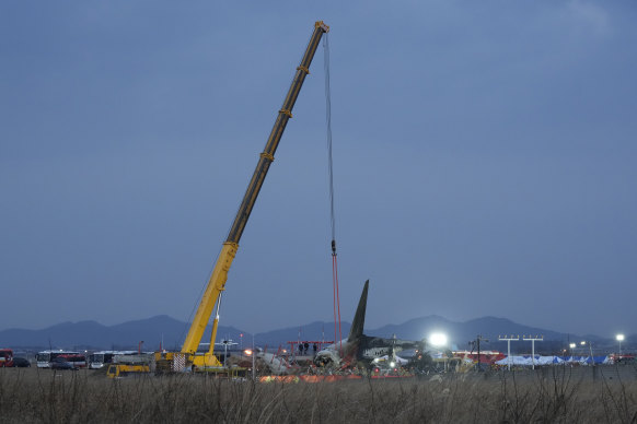 A crane and rescue workers at the site of the crash in Muan-gun.