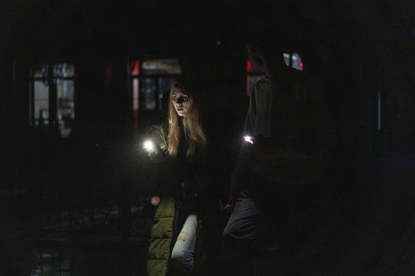 A couple use torches to get around in Kiev’s city centre on Thursday after Russian missile strikes knocked out power.