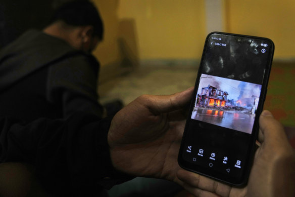 A Myanmar refugee who fled the violence shows a photo of it on their phone in India.