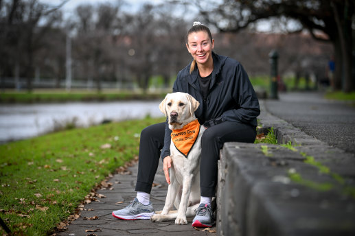 Paralympian Viney near the Princes Bridge rowing sheds with a Guide Dogs Victoria therapy dog called Paolo.