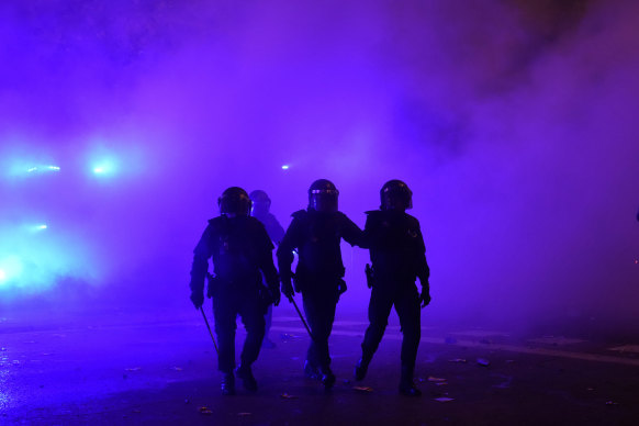 Офицеры полиции по охране общественного порядка ходят в облаке слезоточивого газа во вторую ночь протеста правых демонстрантов в Мадриде во вторник. 