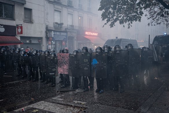 Riot police line up while protecting themselves from objects thrown by protesters in Paris on Saturday.