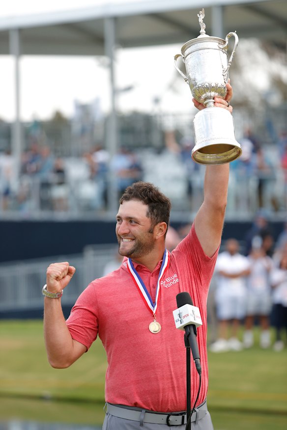 Jon Rahm celebrates with the US Open trophy.