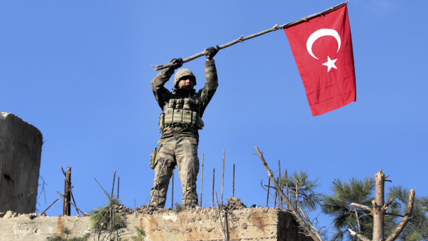 A soldier waves a Turkish flag as Turkish troops secure Bursayah Hill, which separates the Kurdish-held enclave of Afrin from the Turkey-controlled town of Azaz, Syria.