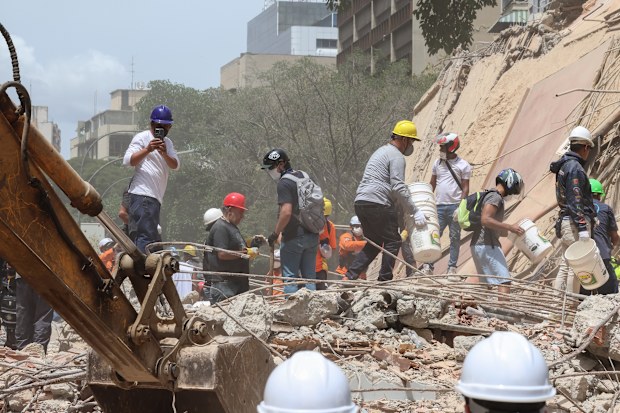 People and rescuers work on the debris of a collapsed building after a magnitude 7.2 earthquake struck Venezuela and other regions in the Caribbean on June 25, 2026 in Caracas, Venezuela