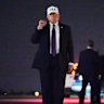 President Donald Trump holds up a fist after disembarking Air Force One at Palm Beach International Airport .