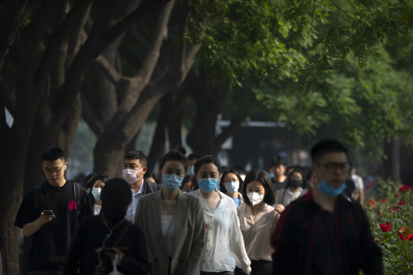 Commuters wearing face masks walk along a street in the central business district during the morning rush hour in Beijing, 
