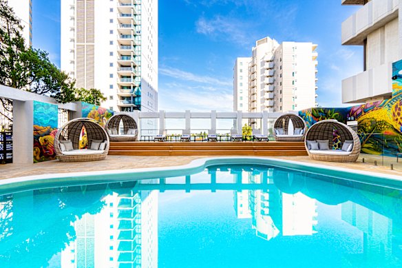 The open-air pool terrace is surrounded by vibrant murals.