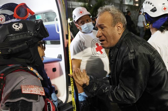 A man speaks to a paramedic in a collapsed building at Los Palos Grandes.