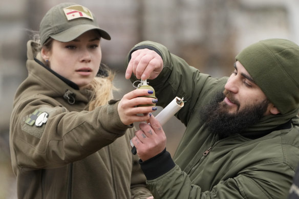An instructor shows a young woman how to use a grenade in Kyiv.