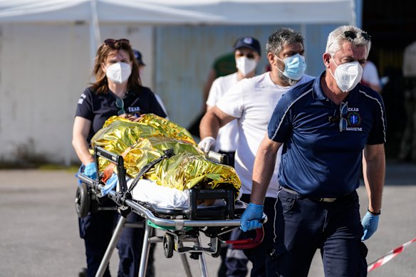 Paramedics carry an injured survivor of a shipwreck to an ambulance at the port in Kalamata.