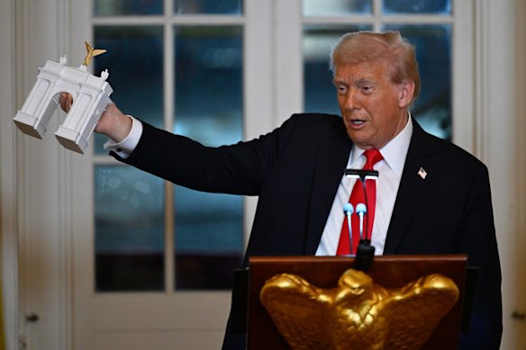 Trump with a model of the arch in October 2025.