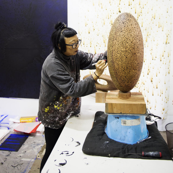 A paint-splattered Lindy Lee at work in her studio.