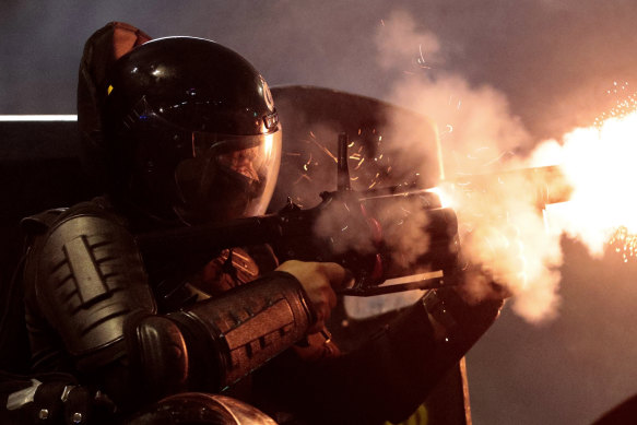 A police officer fires his tear gas launcher.