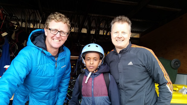 Student Safiol, 8, with Dr Cranky's Bikes for Kids founders Bart Sbeghen, left and Peter Hormann, right, at Flemington Primary School in 2016.