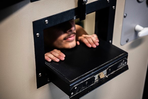 A Silverwater Correctional Centre prisoner peers out of the meal slot in his cell door.