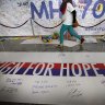 A woman walks past a banner filled with signatures and well-wishes for the missing Malaysia Airlines jetliner MH370 at the Kuala Lumpur International Airport in the days after the plane went missing.