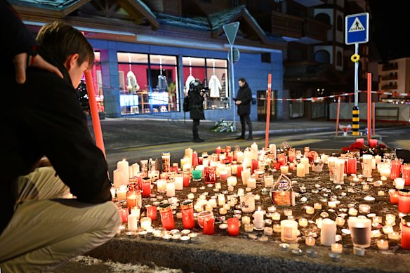 Mourners light candles at the scene of the fire at Le Constellation bar in Crans-Montana.