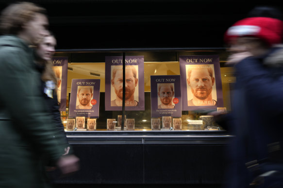 Pedestrians pass a display in the window of a book shop in London.
