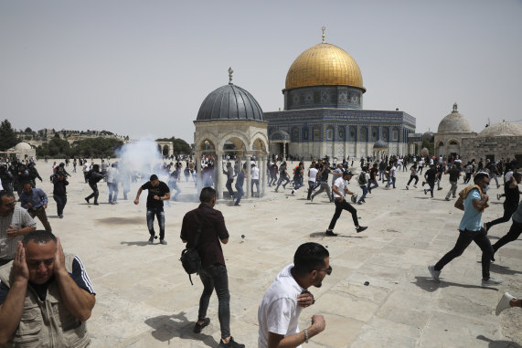 Palestinians run from sound bombs thrown by Israeli police in front of the Dome of the Rock shrine at al-Aqsa mosque complex in Jerusalem on Friday,