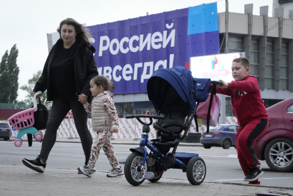 A woman and her children cross a street, with a huge poster reading ‘With Russia forever!’ in the background in Luhansk, Luhansk People’s Republic controlled by Russia-backed separatists, eastern Ukraine.