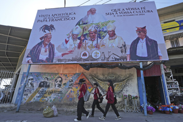 A billboard welcoming Pope Francis stands above a mural honouring sanctioned Bishop Belo and three others as national heroes in Dili, Timor-Leste.