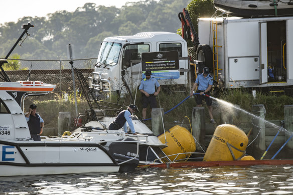 Water police, police divers and Maritime NSW attend to the boat that was engulfed by fire at Hawkesbury River Marina on Sunday.