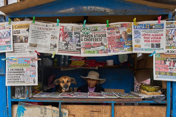 Nicolasa Munoz waits for customers next to her dog Mona while tending her newspaper stand in Lima, Peru.