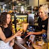Expresso co-owner Jessica Kotzen, receives payment from customer Amber Boardman at her cafe in Brookvale, Sydney.