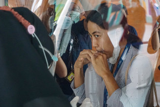 A woman blows air in a plastic bag to be tested for COVID-19 at Bali airport.