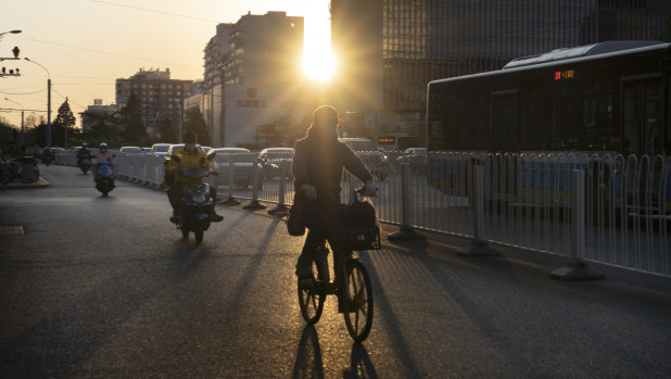 Cyclists ride along a road as the sun sets in Beijing.