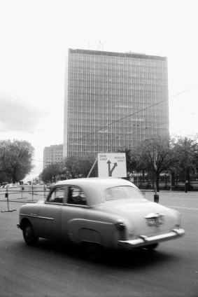 A car drives up Spring Street and past the building in 1958.