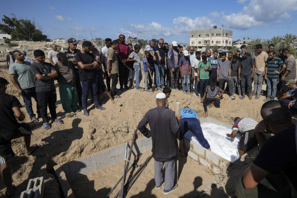 Palestinian grave digger Sa’di Baraka, center, oversees a burial in the cemetery in Deir al-Balah, Gaza Strip.