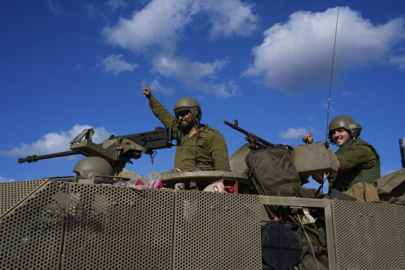 Israeli soldiers raise their fists from a moving APC in northern Israel near the Israel-Lebanon border on Tuesday.